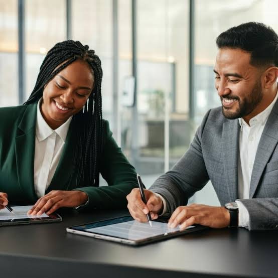 Two professionals reviewing and signing a financing agreement on a tablet.