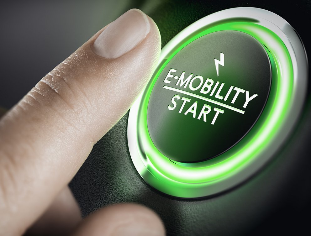 Close-up of a finger pressing an illuminated E-Mobility Start button.