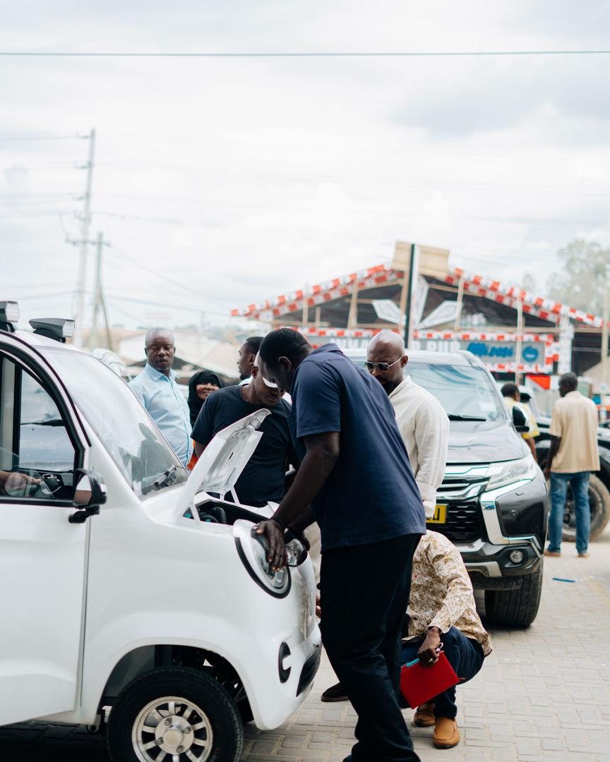 A group of people gathered around a Mobility Ventures vehicle with the hood open.