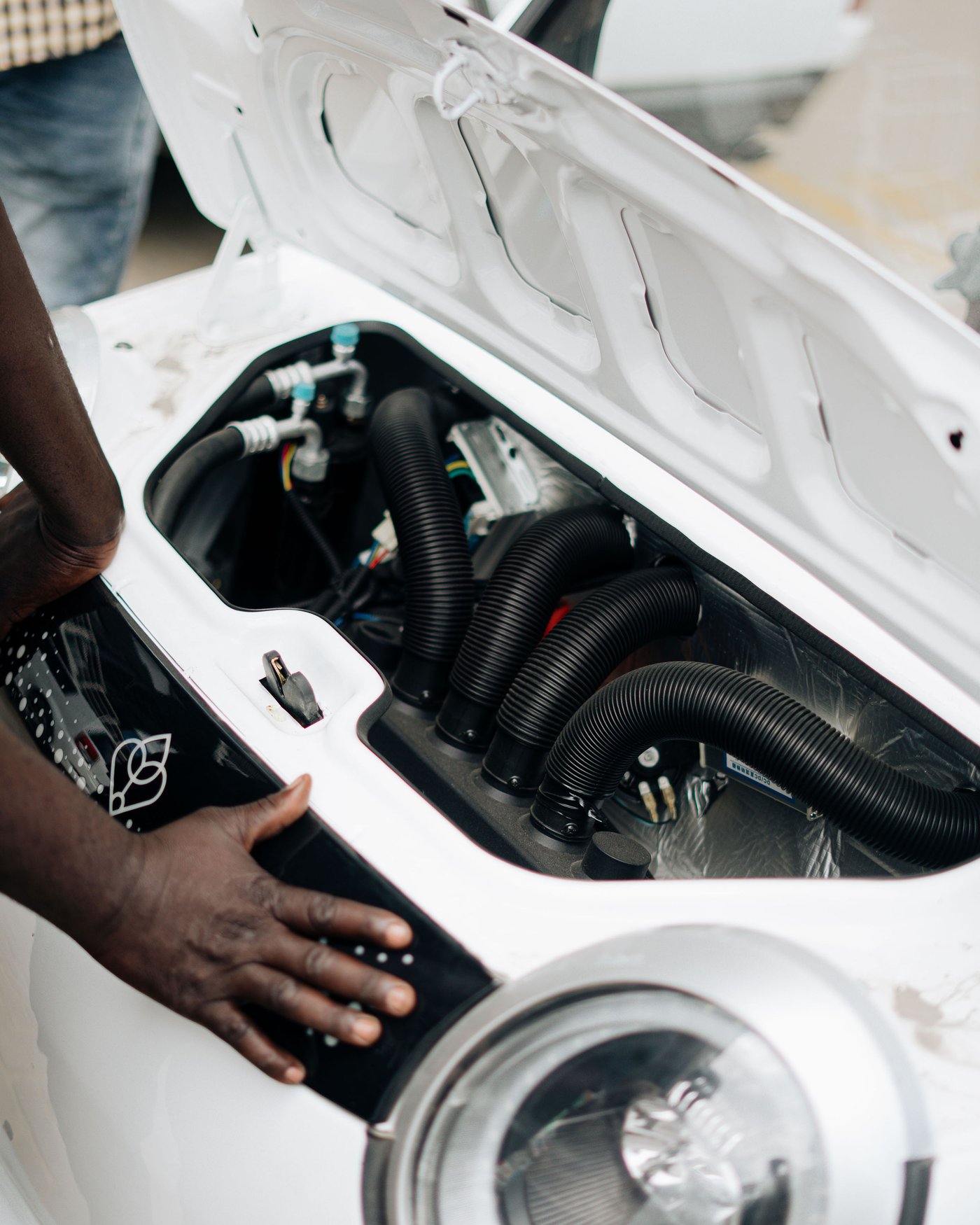 Technician's hand on the open battery and drive compartment of a Mobility Ventures electric vehicle.